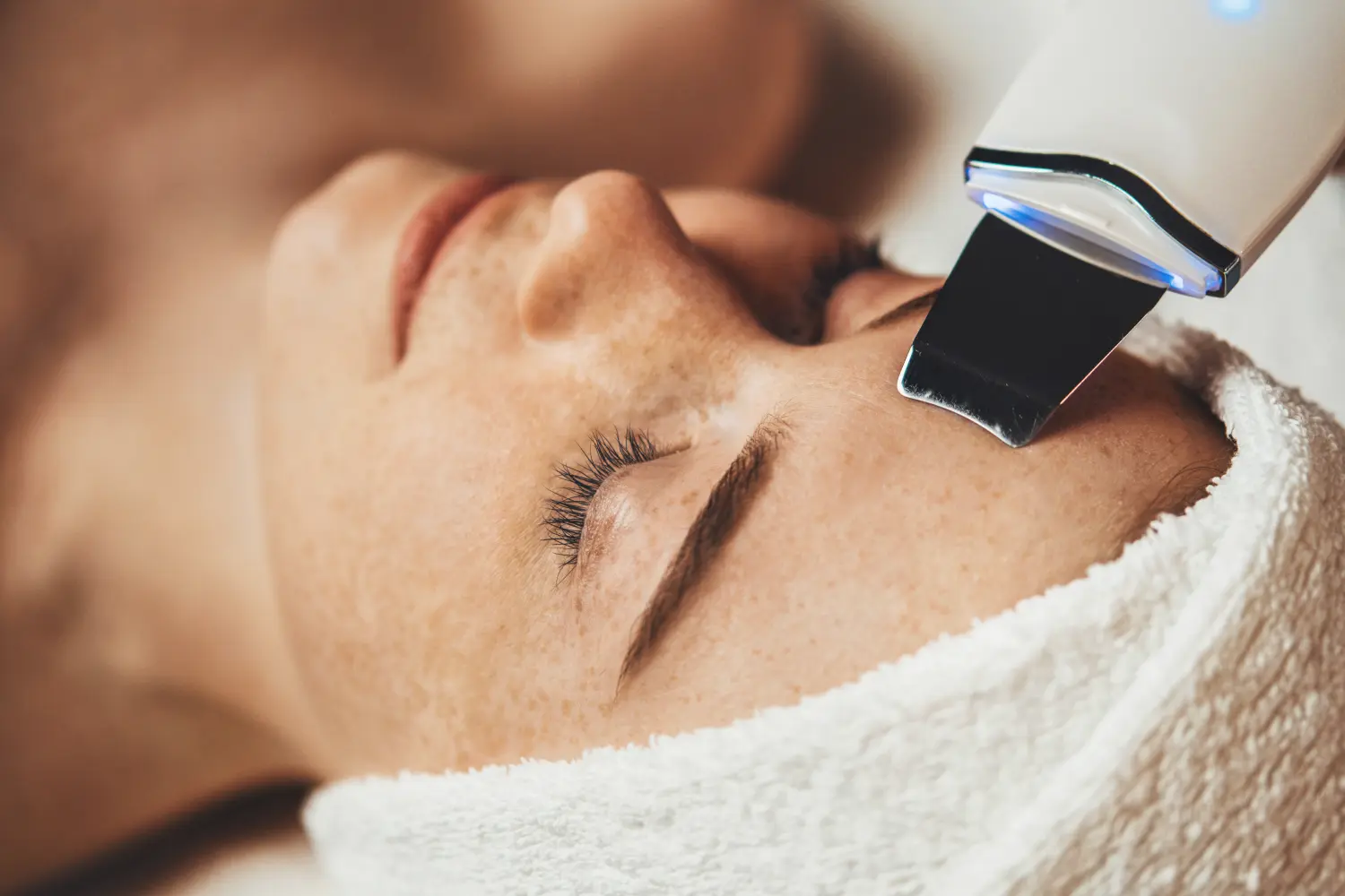 Kaukasische, sommersprossige Frau erhält Gesichtskavitation im Spa-Salon. Professionelle Peeling-Hardware. Elektrische Spa-Ausrüstung. Medizin-Patientengerät